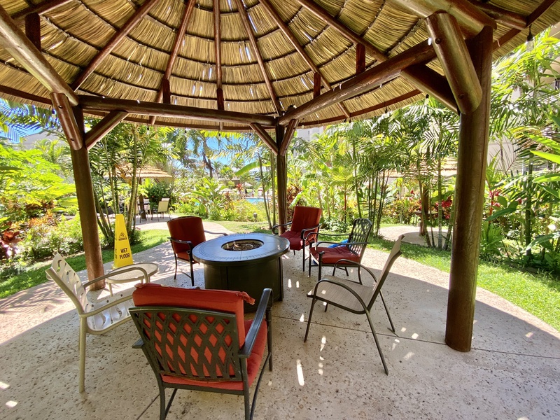 The resort features a cozy outdoor seating area under a thatched gazebo, perfect for relaxing with friends or enjoying the garden views.