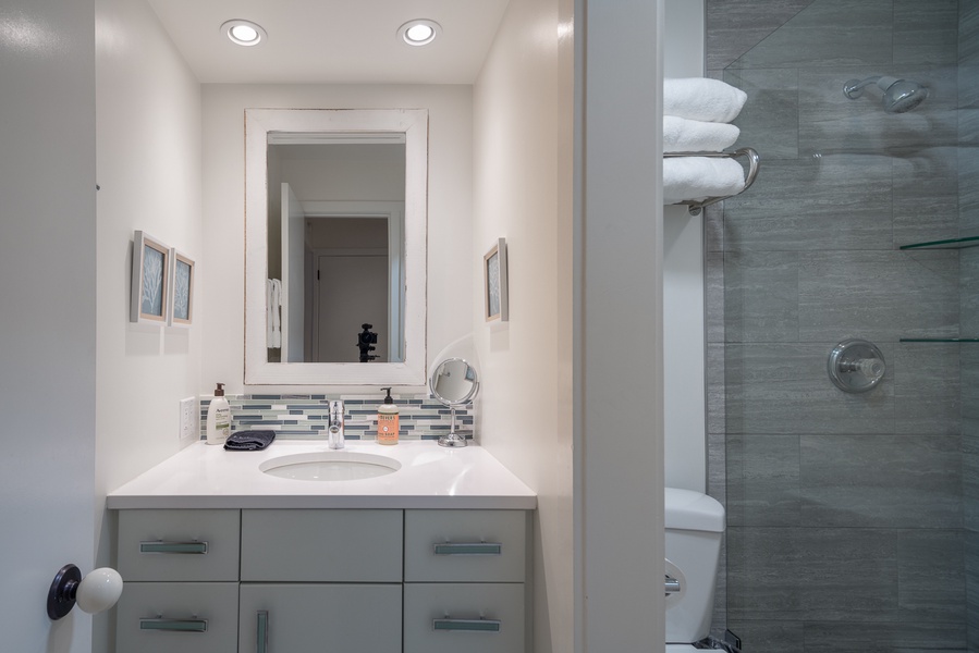 Refresh and rejuvenate in this pristine bathroom oasis, boasting a sleek vanity, well-lit mirror, and plush towels ready to envelop you in comfort.
