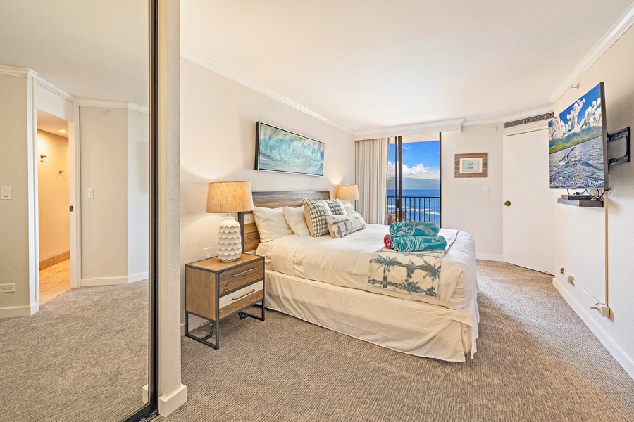 Kaanapali Shores 903’s bedroom features a cozy bed, vibrant decor, and private lanai access.