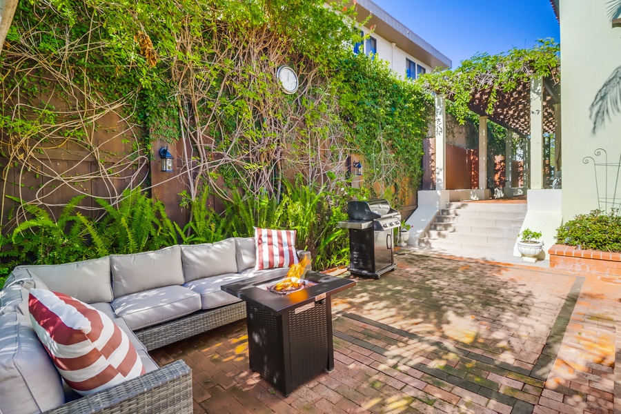 Gather around the fire pit in this cozy outdoor lounge area. Perfect for evening conversations, the space also features a grill, making it an ideal spot for a casual barbecue with friends and family.