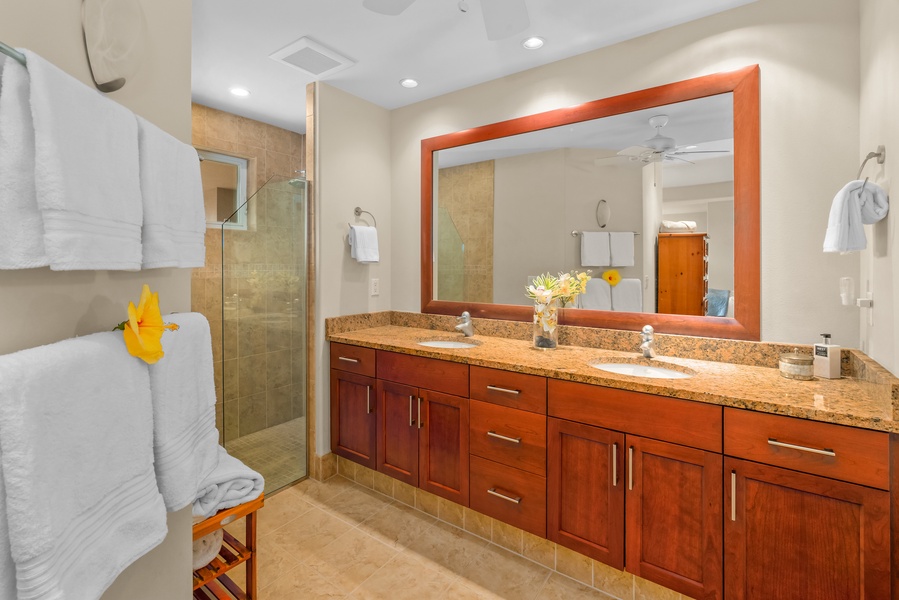 The ensuite bathroom, features a walk-in shower, double sinks, and a private water closet, adding a touch of spa-like luxury.
