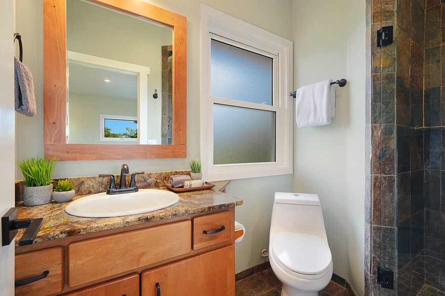 Refresh in your stylish bathroom featuring granite countertops, natural wood accents, and a spacious slate-tiled shower.