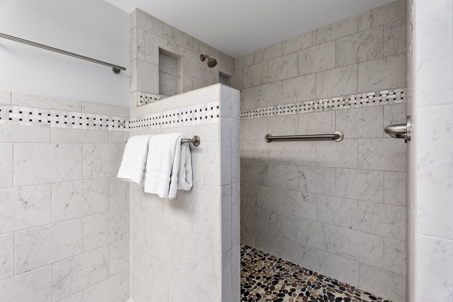 Spacious walk-in shower with pebbled flooring for added comfort.