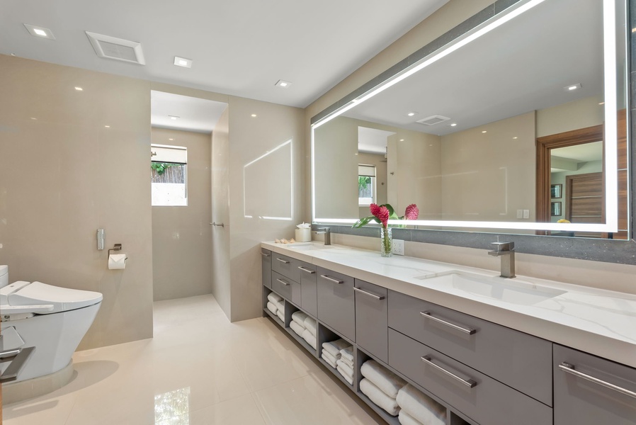 Your private bathroom sanctuary features a spacious double vanity with sleek modern fixtures, where soft lighting and fresh florals create a spa-like atmosphere for your daily routine.