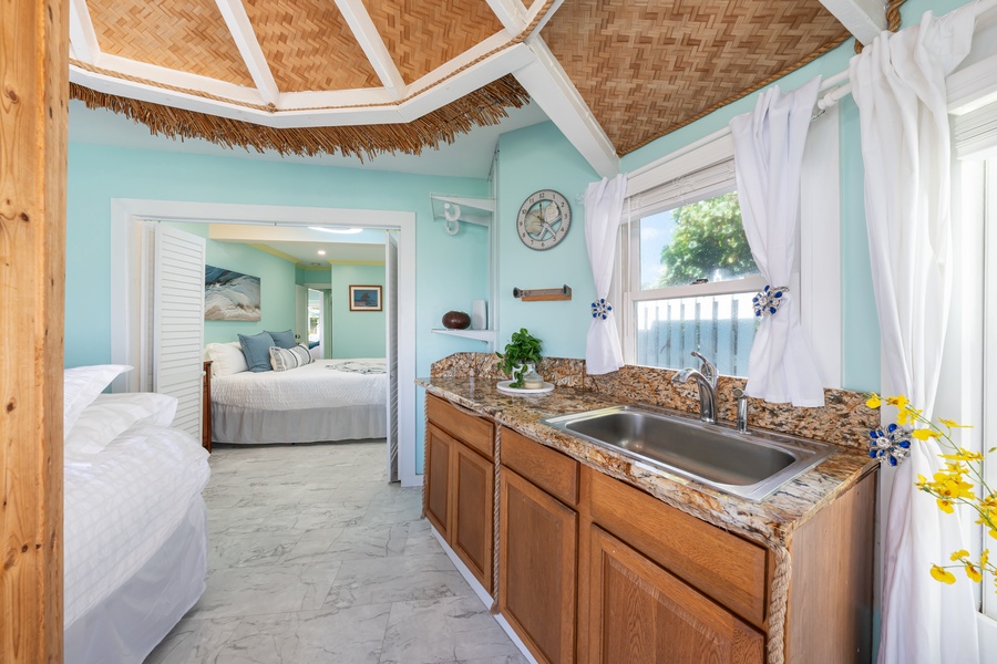 Tropical retreat with woven ceilings, turquoise walls, and a cozy in-room kitchenette.