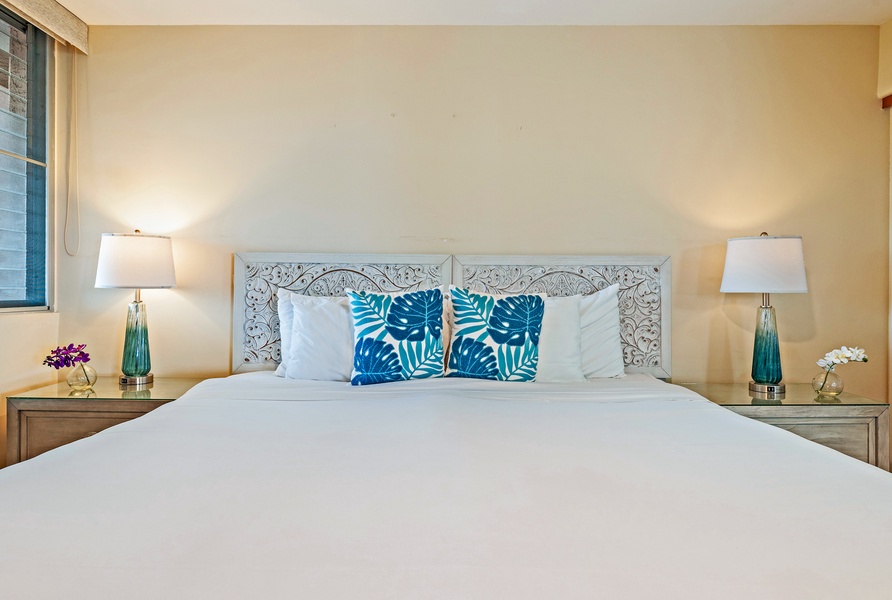 The guest bedroom at Royal Kahana 610 features a cozy king-sized bed with tropical-themed pillows.