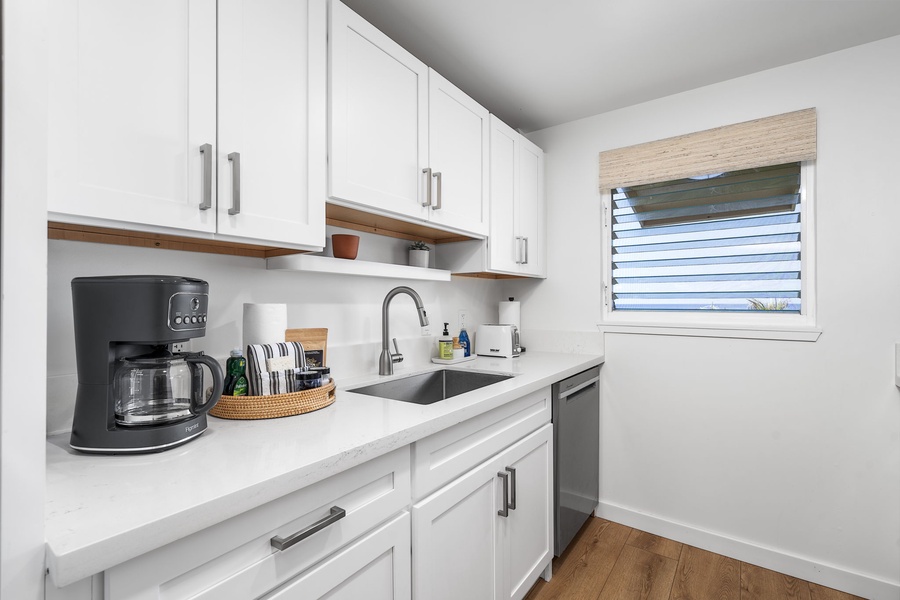 White shaker cabinets, open shelving, and modern touches bring elegance and ease to this fully equipped kitchen.