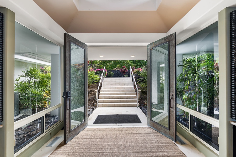 Grand entrance with tropical landscaping and elegant stairway leading to the property.