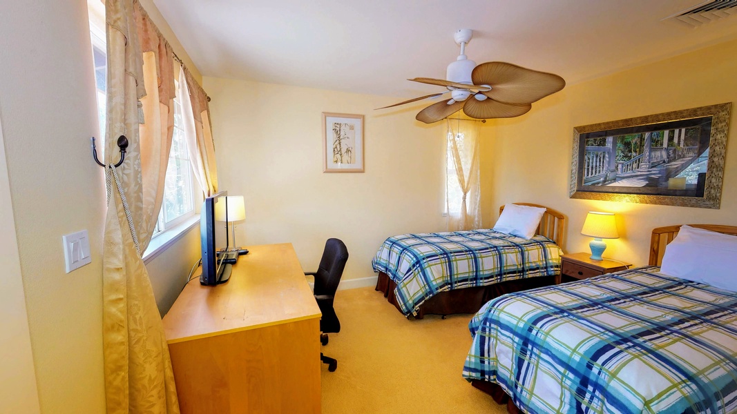 The second guest bedroom with twin beds, a desk and TV.