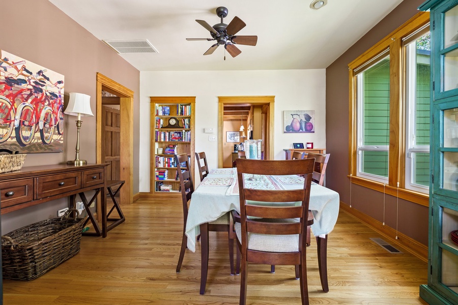 Your dining space features warm wood floors, charming built-in bookshelves, and natural light streaming through colorful shutters—perfect for morning coffee or evening meals.
