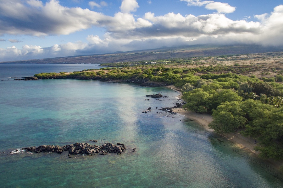 Scenic coastline with calm, clear waters and lush greenery—an ideal spot for peaceful nature walks and ocean views.