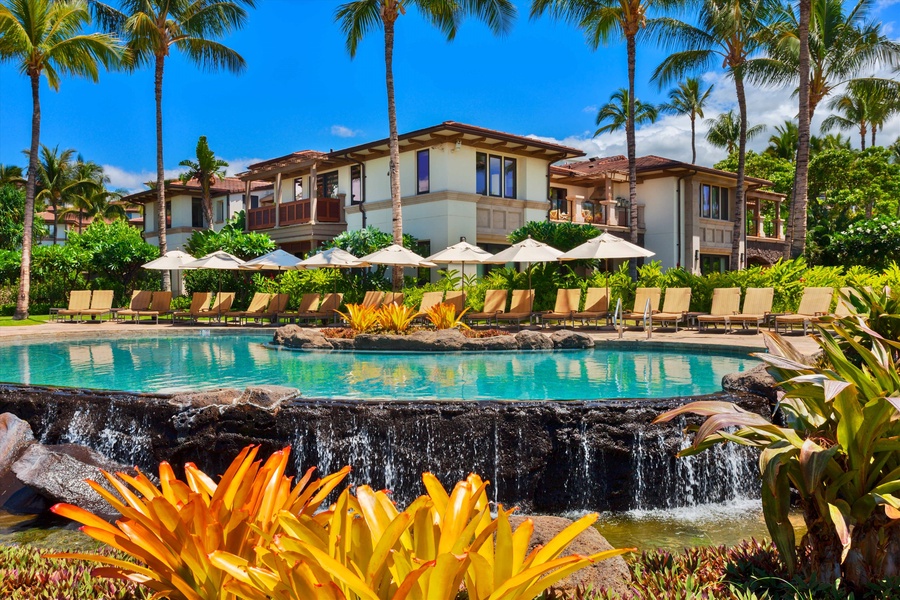 Resort-style pool with cascading waterfalls and sun loungers, offering a luxurious tropical escape for relaxation and leisure.