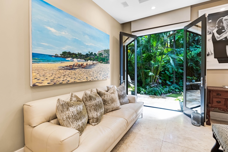 Lounge area with a plush sofa, art, and open-air garden access.