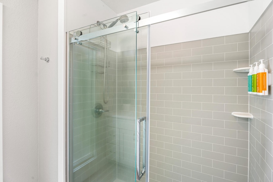 Contemporary walk-in shower with clean subway tile and sliding glass door.