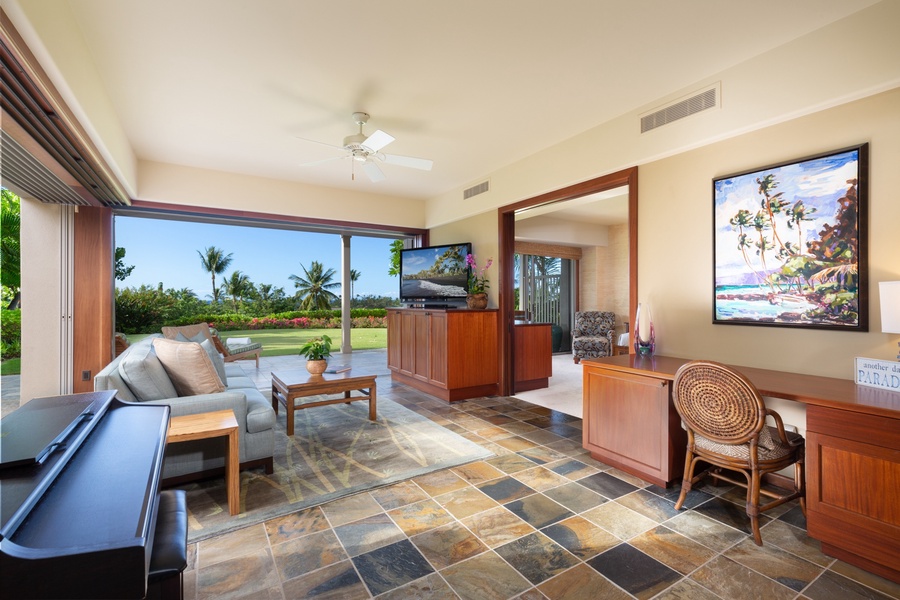 Retreat room with flat screen television, desk, plush seating and lanai.
