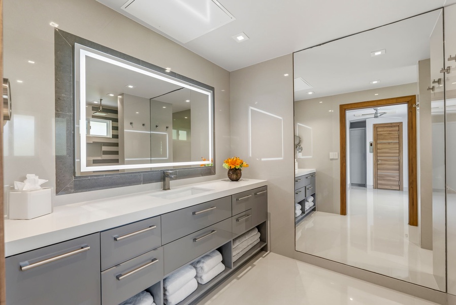 Step into your spa-like ensuite, where a sleek double vanity with elegant LED mirror lighting and pristine white countertops sets the tone for indulgent mornings. Plush towels await as natural light filters through glass, creating a serene sanctuary for yo