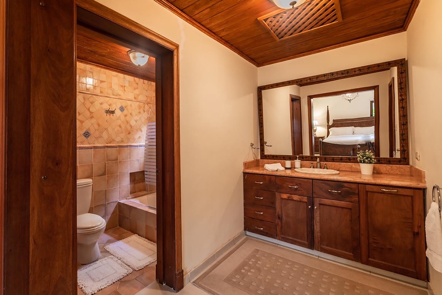 Enjoy a refreshing bath in the full ensuite with a sink, wooden cabinetry, and a large vanity.