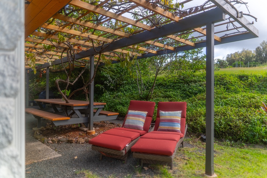 Relax under this stylish pergola, surrounded by lush greenery and comfortable lounge seating for a peaceful outdoor retreat.