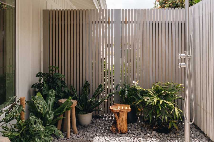 A private outdoor shower surrounded by tropical greenery and natural stone.
