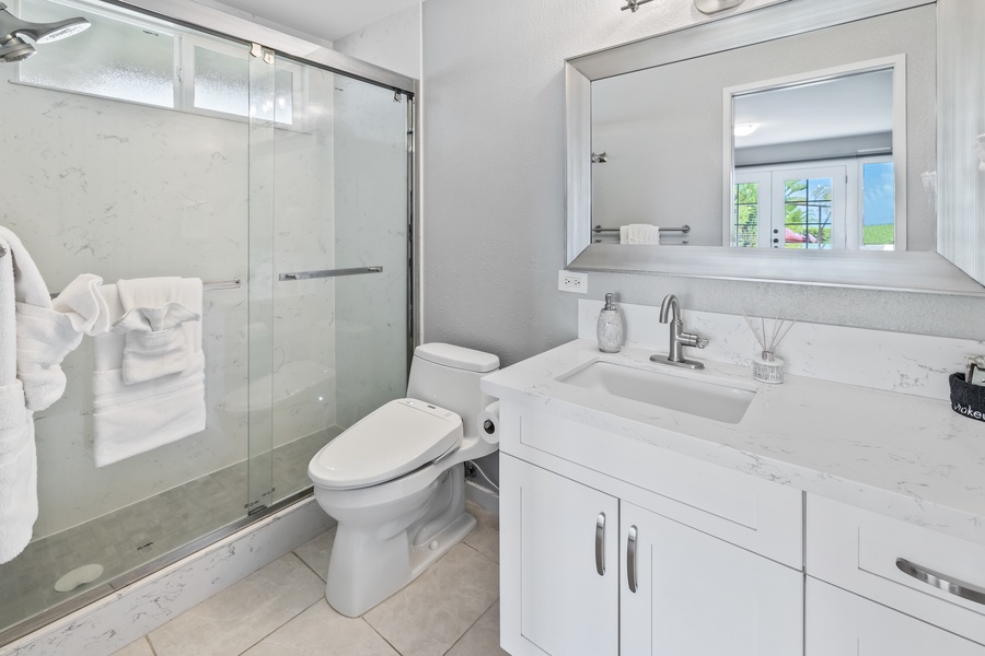 Bright and modern shared bathroom with a glass shower and sleek vanity.