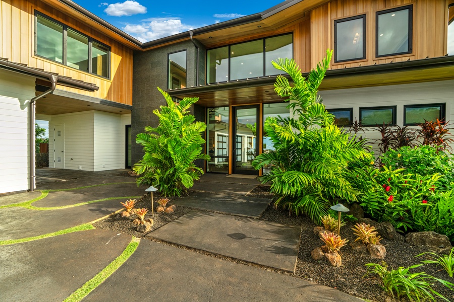 Modern tropical architecture welcomes guests with lush landscaping and contemporary design elements at the property entrance.