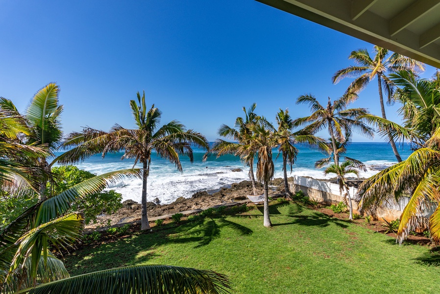 A hammock strung between palms invites you to unwind as waves roll in behind you.