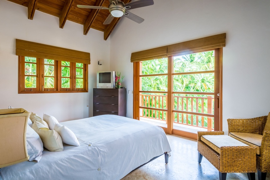 Sunny guest bedroom features a comfortable bed and sliding doors leading to a private patio.