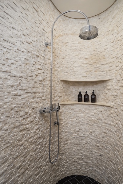 Luxurious curved stone shower with built-in shelf for your toiletries and rainfall showerhead for a spa-like experience.