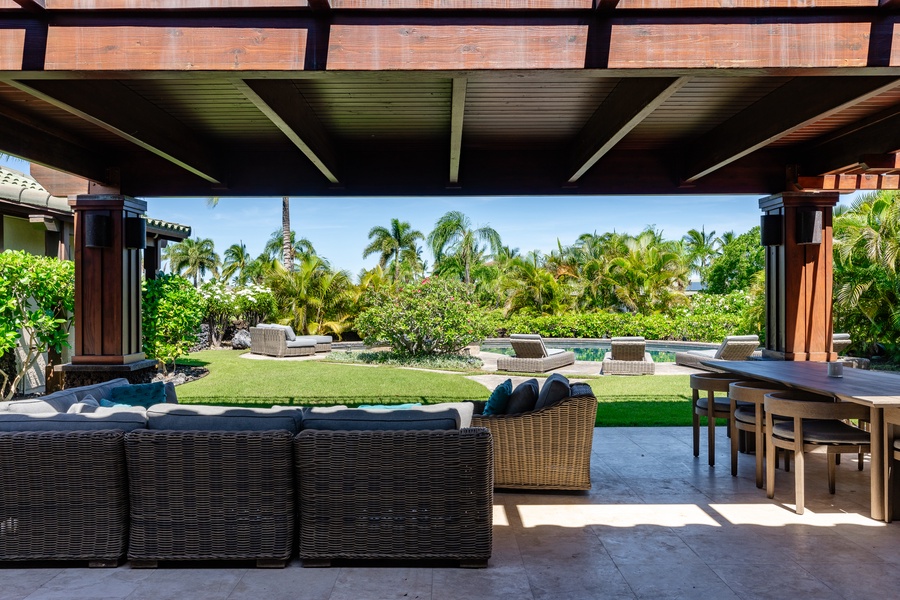 Spacious covered outdoor seating area with views of the pool and lush tropical garden