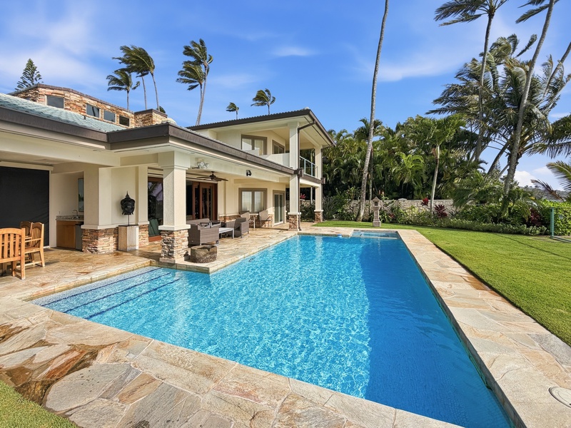 Tropical luxury estate featuring crystal-clear pool surrounded by swaying palms and manicured lawn.
