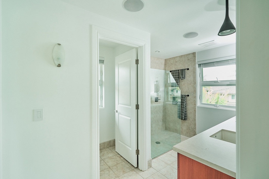 Your spacious bathroom features a sleek glass shower, modern fixtures, and warm natural light streaming through the window.