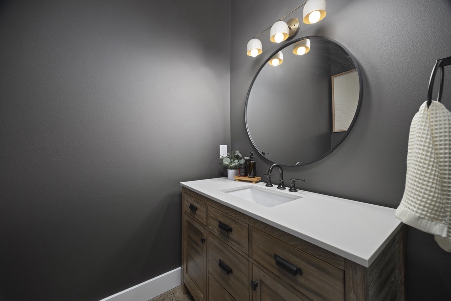Modern guest bath featuring round mirror detail, wood vanity, and warm ambient lighting.