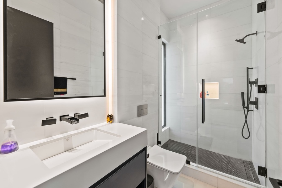 Modern bathroom with glass shower, floating vanity, and clean finishes.