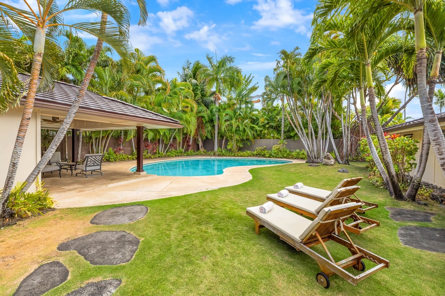 Lush tropical paradise with a private pool and sun loungers.
