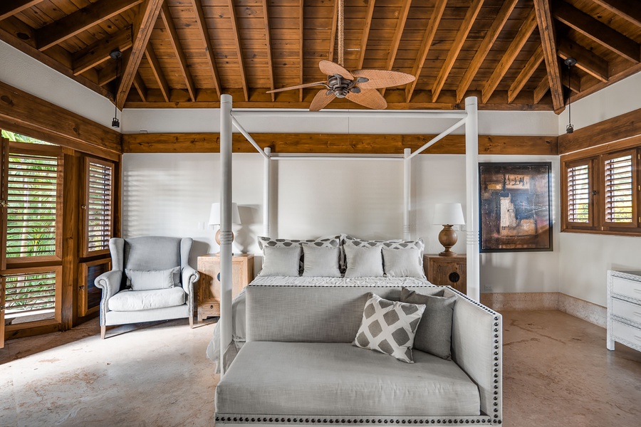 The secondary suite offers a four poster king bed with a footboard bench and TV.