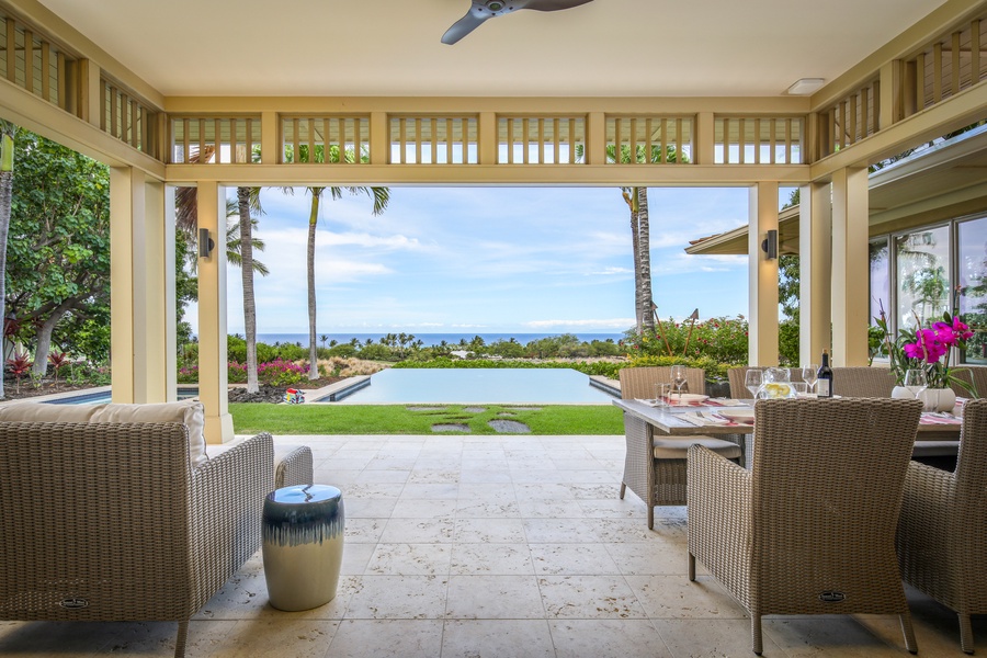 View of the pool deck and grassy lawn from the ample covered lanai.