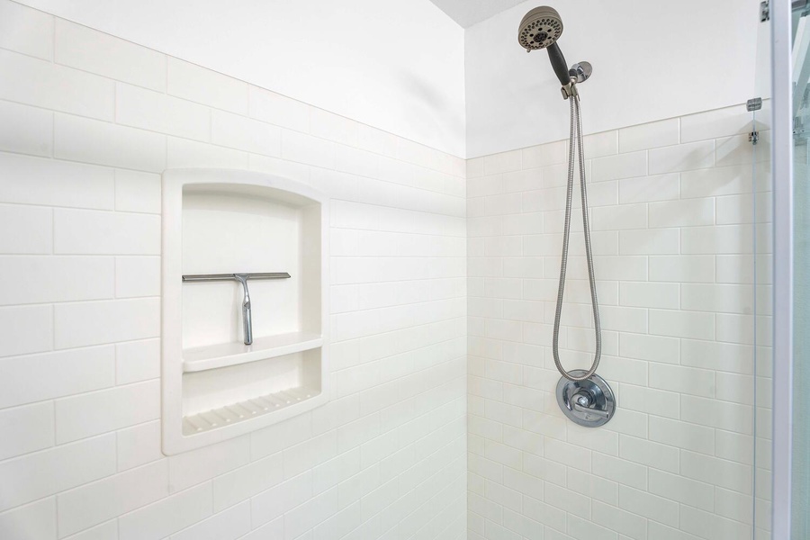 The primary ensuite has crisp white tile detailing.