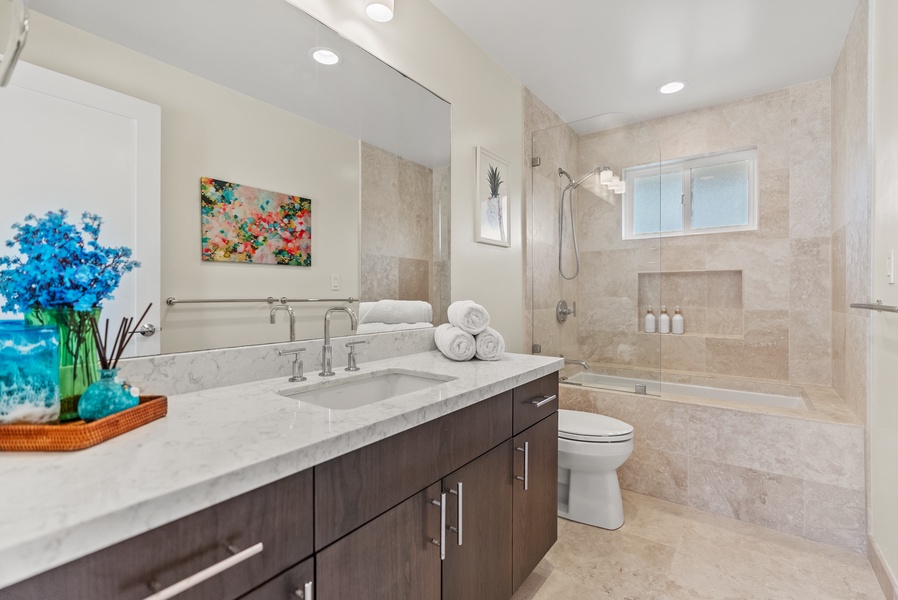 The shared bathroom in the upper-level guest bedrooms has a shower/tub combo and ample vanity space.