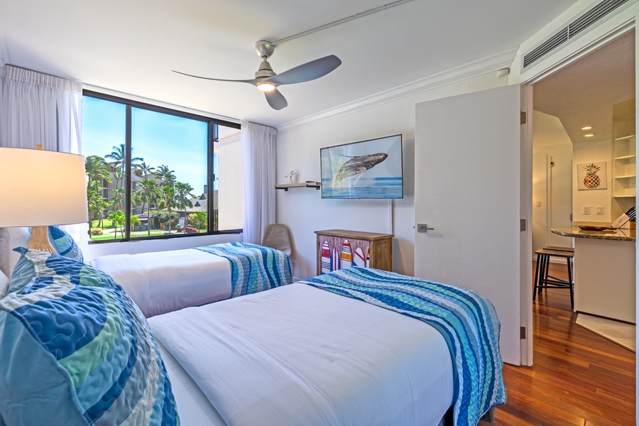 Garden-view guest room at Kaanapali Shores 213, with cozy beds and a TV, perfect for a peaceful night in.