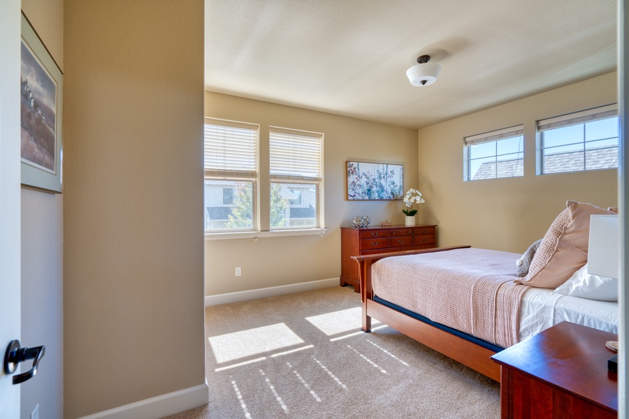 Windows in the second bedroom bring in natural light, enhancing the cozy and comfortable ambiance
