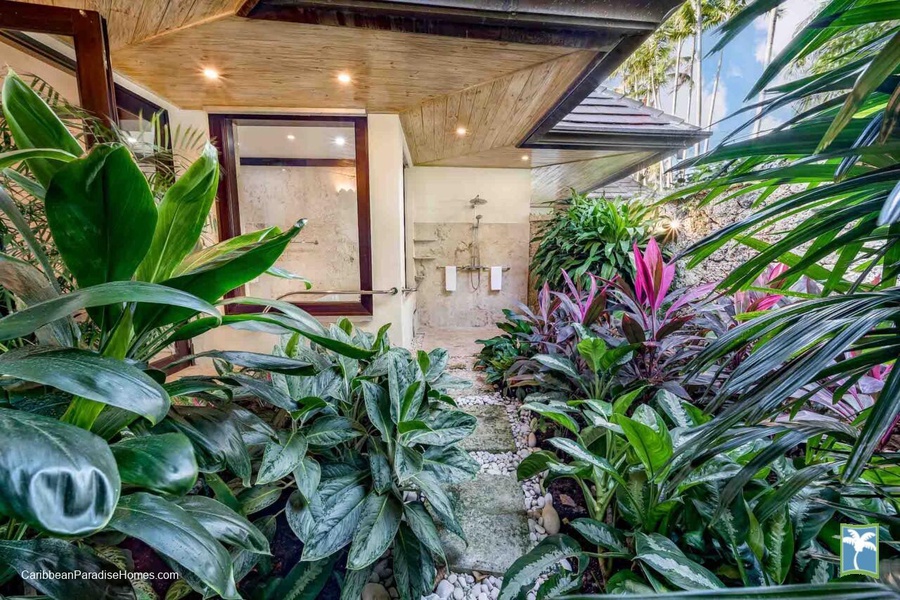 An outdoor shower surrounded by tropical plants, blending nature with luxury.