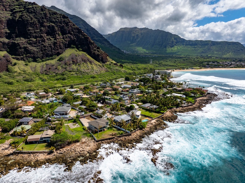 A lush mountainside backdrop meets modern coastal architecture in this view from behind the estate.