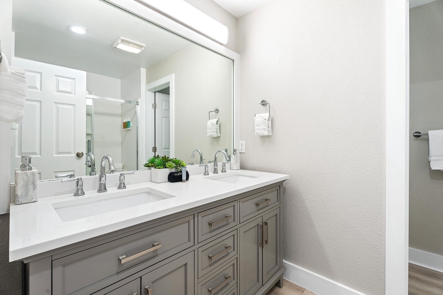 Modern primary bathroom with dual sinks, sleek fixtures, and ample vanity storage.