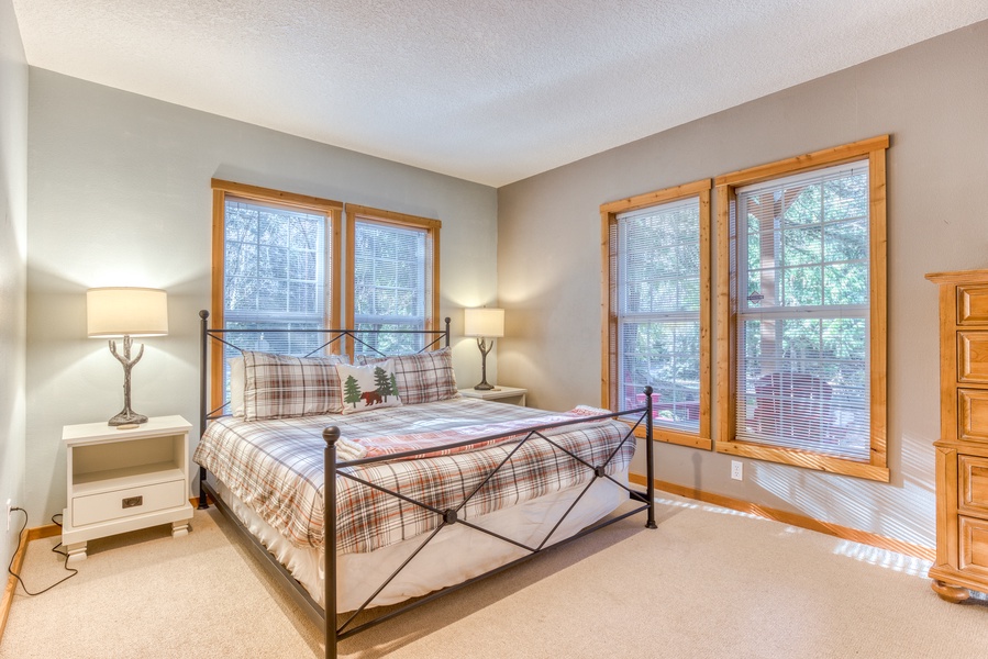Main-level bright and cozy bedroom with a king bed and windows providing natural light.