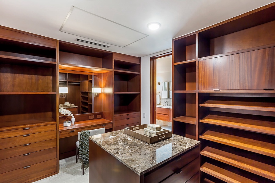 A spacious and elegant walk-in closet with ample storage and a marble-topped island for added luxury.