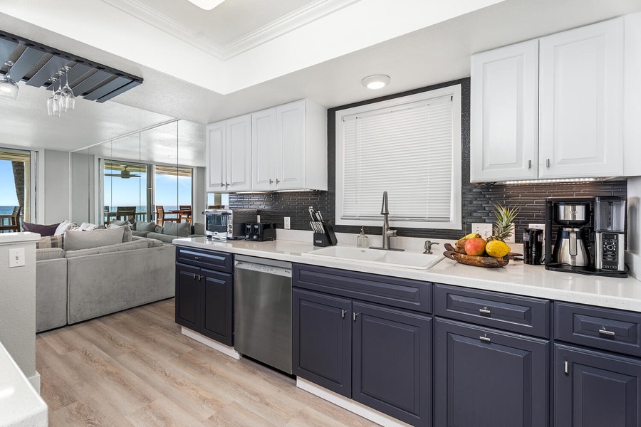Modern kitchen with dual-toned cabinetry, dishwasher, and full-size sink overlooking the sea.