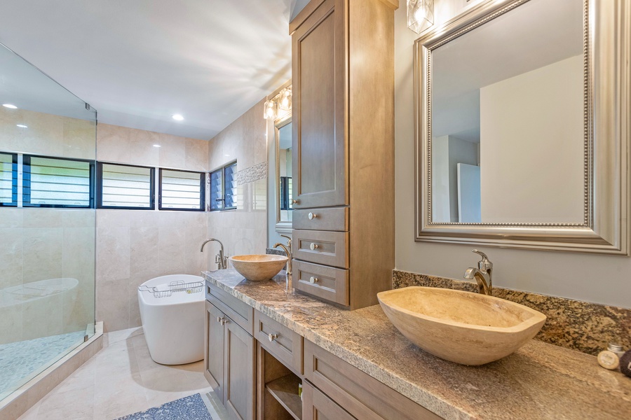 The luxurious bathroom features dual stone vessel sinks and a spacious vanity area, complemented by a modern standalone soaking tub