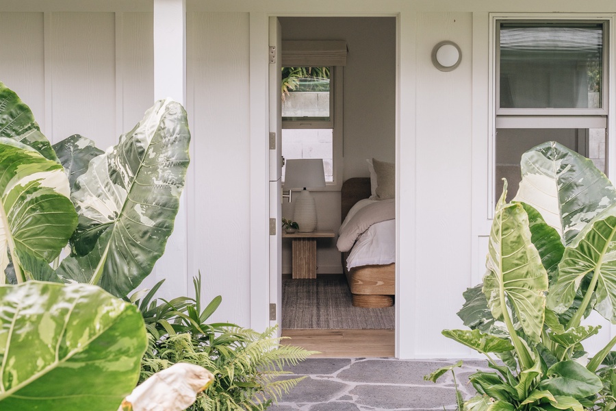 A welcoming entrance framed by tropical greenery leads to this peaceful bedroom retreat.