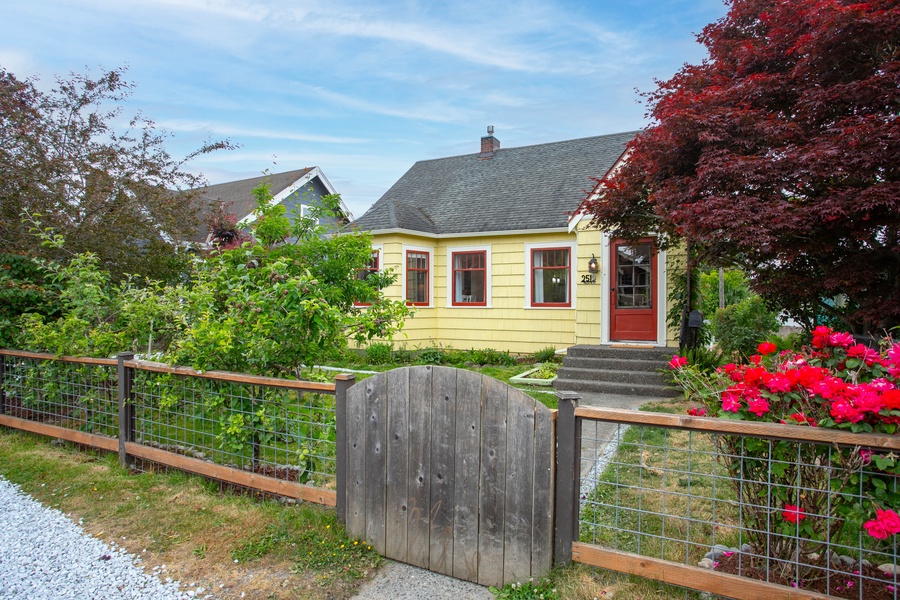 The welcoming front entrance is framed by lush landscaping and a charming fence line, offering instant curb appeal.