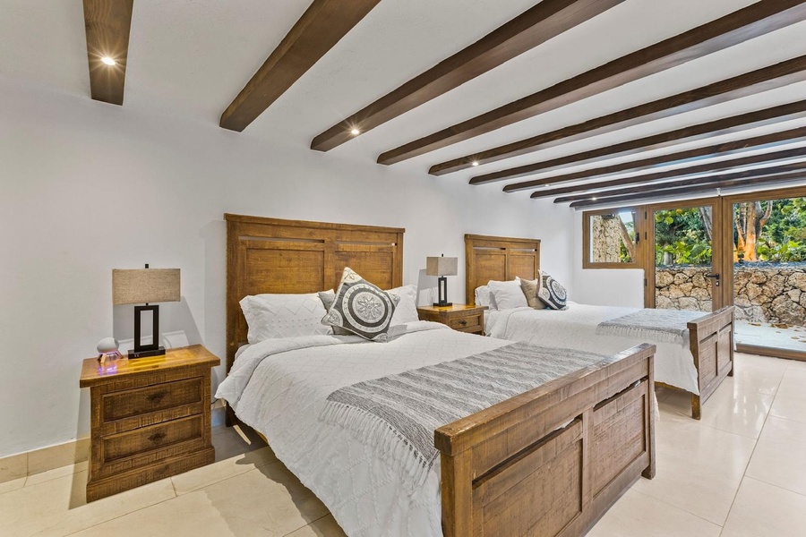 Retreat in the guest bedroom with two comfortable beds and large windows offering garden views.
